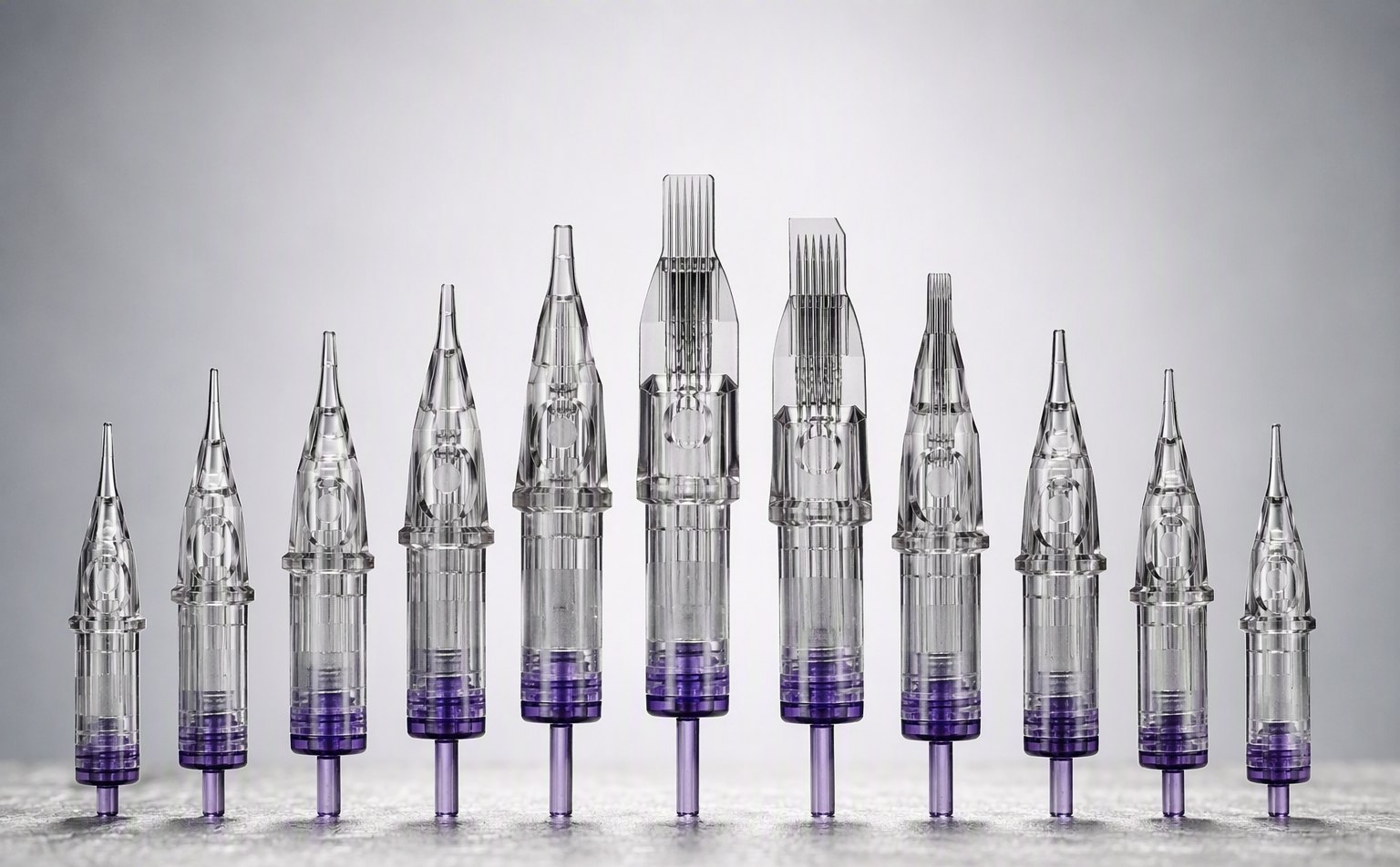 Row of tattoo needle cartridges with transparent housings and purple caps